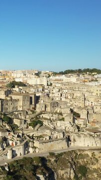 Wide view of Matera's historic stone buildings under a clear blue sky, showcasing the unique architecture of this southern Italian city.