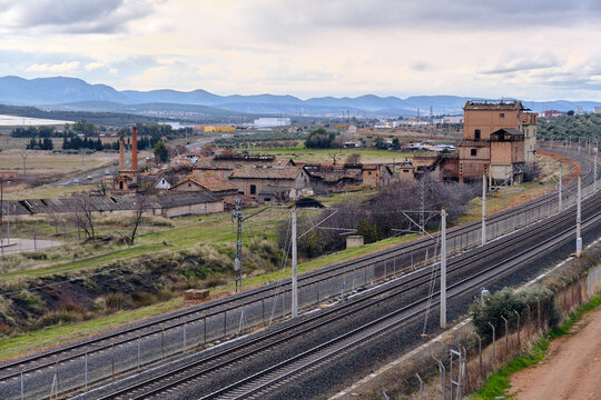 Industrial Decline And Abandonment In Puertollano Spain A Derelict Factory And Railway Tracks Under A Cloudy Sky Representing Economic Downturn And Urban Decay