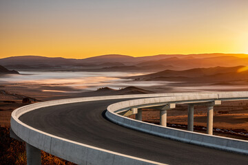 Curved concrete highway bridge overpass overlooking a misty valley landscape during a beautiful golden sunset in China.