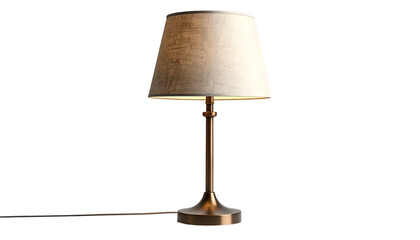 Obraz premium A gold-toned desk lamp with a beige lampshade stands isolated against a black backdrop