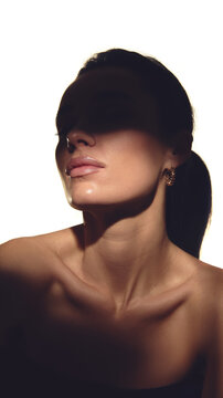 Female portrait with dramatic shadow light highlighting skin and jewelry. Concept of skincare advertising, luxury accessories promotion, premium cosmetics and beauty branding campaigns.