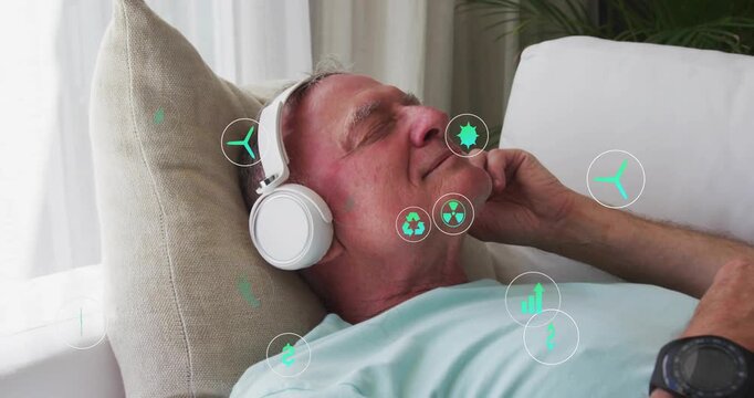 Senior man reclining couch touching headset teal icons drifting around torso showing health vitals
