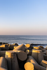 Fototapeta premium ocean waves crashing against tetrapod sea barrier at golden hour coastline
