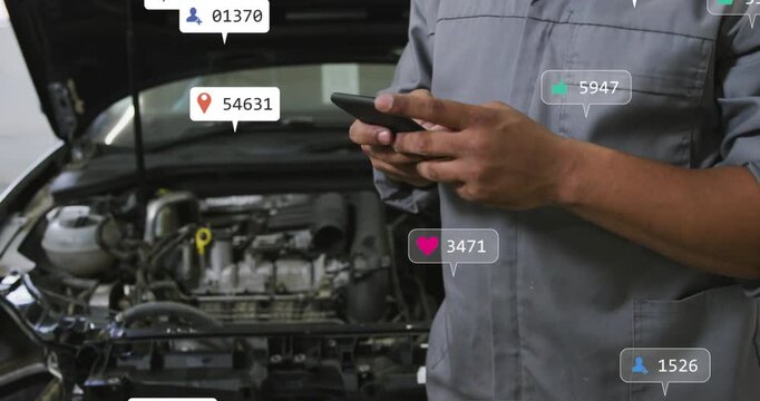 Reacting to notification bubbles appearing, mechanic in grey shirt tapping smartphone by car engine