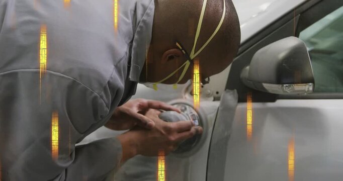 Male mechanic leaning over silver car, noticing and adjusting circular fender cover for repair
