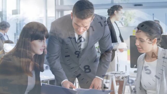 Pointing, suited man guiding two teammates through binder in office with watch and clock graphic