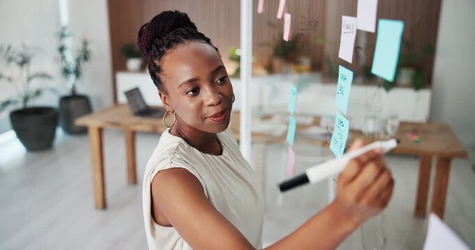 Glass wall, planning and black woman writing in office with research, ideas or information for creative project. Board, stick note and magazine editor with article mind map for publishing in agency.
