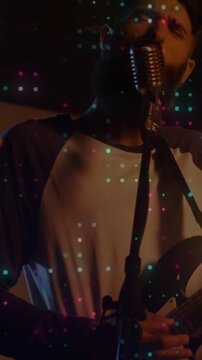 Vertical video: Camera panning frontman strumming, singing and performing with teal dots overlay
