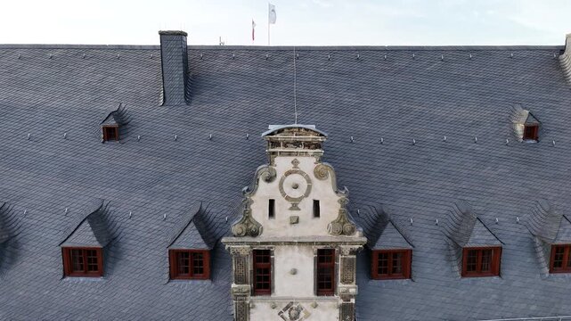 Drone frames the sundial near the main entrance then rises to reveal the tower behind from below.