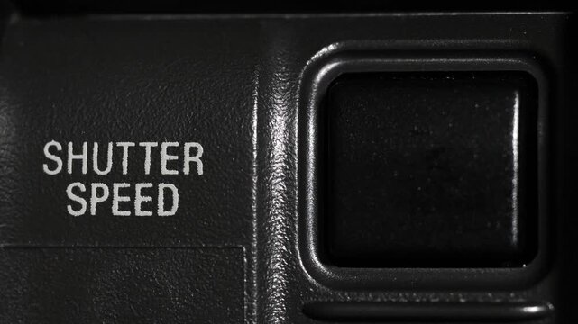 Close up of finger pressing shutter speed control button on camera body