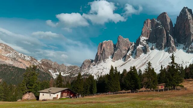 Dramatic mountain peaks rising above forest and traditional alpine hut. Dolomites, Zanser Alm, South Tyrol