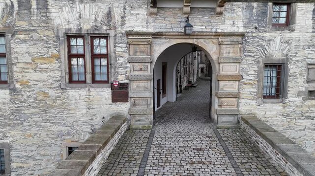 Drone flies very close to the main entrance and rises slowly, showing signage on the castle facade.