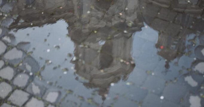 The bell tower of the Church of Sant'Agnese in Agone reflected in a puddle in Piazza Navona, Roma.
