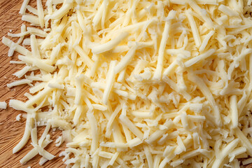Fototapeta premium Shredded cheese on cutting board for cooking and baking