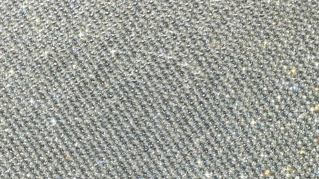 Seamless Rotating Silver Sparkling Crystals. Macro video of faceted rhinestones with intense bright star flares and smooth rotational camera movement on light surface in true seamless loop.