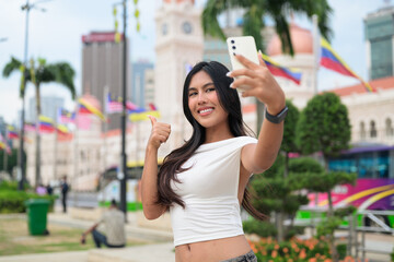 Thai Woman at Merdeka Square Kuala Lumpur using phone in front of the Sultan Abdul Samad Building.