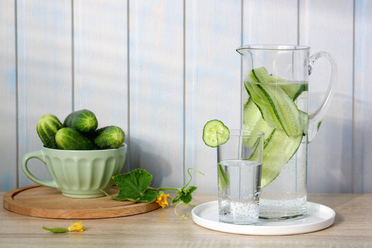 Refreshing cucumber detox water with sliced cucumbers in a glass pitcher and an individual serving glass, promoting healthy hydration and wellness on a table