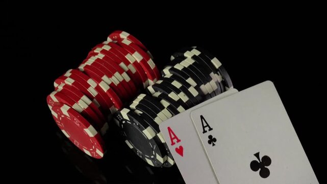 Close-up of playing cards and poker chips in a sequence showing the reveal of an Ace of Hearts and an Ace of Clubs on a reflective surface