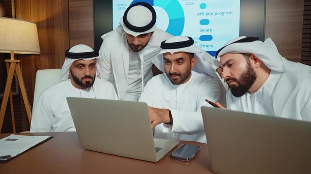 Emirati businessmen making a business conference in an elegant room. Four arab businessmen in traditional attire discussing financial charts during a podcast meeting
