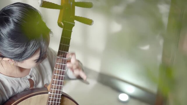 Beautiful young expertly musician violin fingerboard playing ruan traditional musical stringed instruments, creating a symphony of sound. The image highlights the dedication and love of music on stage