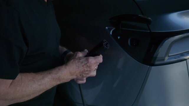 older male unplugs his EV charging cable and inspects the inside of the outlet for cleanliness after he is done