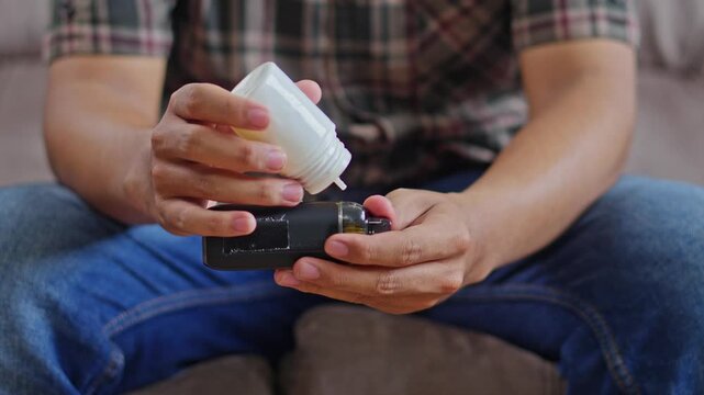 Close-up of Hands preparing an electronic vaping device by refilling cartridge