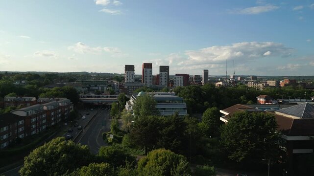 An aerial view shows a suburban landscape with modern buildings, lush trees, and a highway.