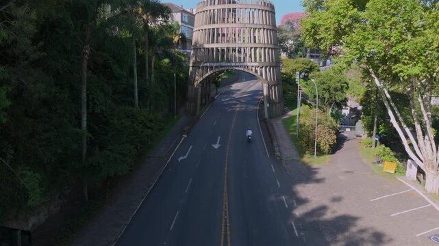 Wine barrel shaped city gateway over urban avenue in Bento Gon&ccedil;alves with aerial forward approach, captured in D-Log with 10-bit color using a Hasselblad sensor.