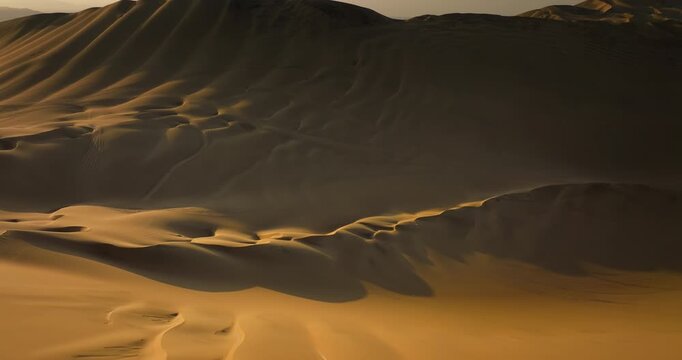 Aerial view of beautiful golden sand dunes with wind patterns in the desert near Huacachina oasis at sunset, Peru. Copy space