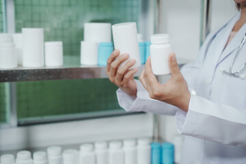Pharmacist or lab technician in white coat holding blank pill bottles in a pharmacy storage room, checking medicine containers on shelves, healthcare and pharmaceutical inventory concept.