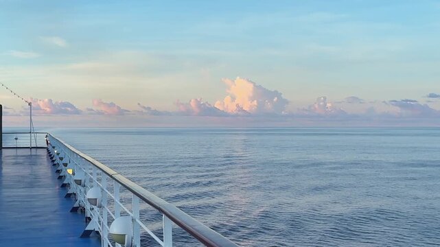 POV from a cruise ship looking aft then panning right across a pink glowing sunset in the horizon in the Mozambique Channel