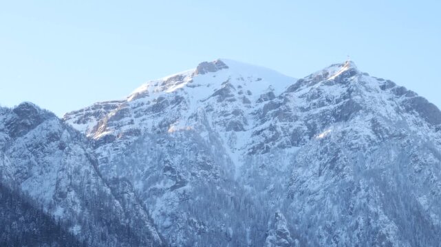 Close view of the snow-covered peaks of the Bucegi Mountains in winter, rising above the town of Busteni in Romania. Scenic Carpathian mountain landscape under clear blue sky.