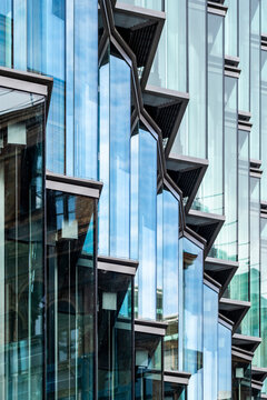 Steel and glass office facade with windows showing reflections in grid geometry pattern for corporate architecture background and modern design
