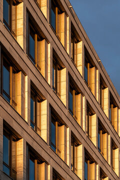 Golden sunlight on corporate office facade with windows creating grid geometry pattern in modern architecture background for business visuals