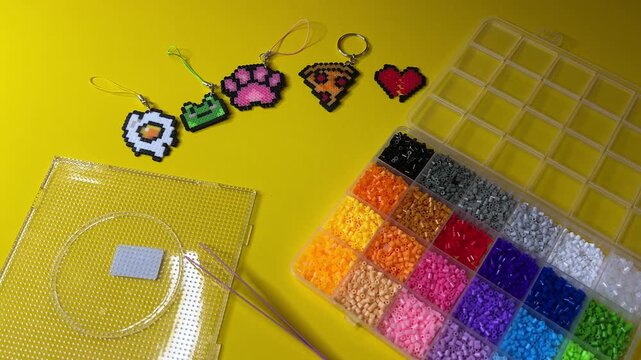 A horizontal video demonstrating a kit for making keychains at home using thermoplastic beads that need to be heated with an iron.