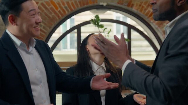 Three multiracial business emotional men team ignoring Asian woman with document Japanese annoyed businesswoman trying to talking to busy African Korean businessmen discussing gender problem in office