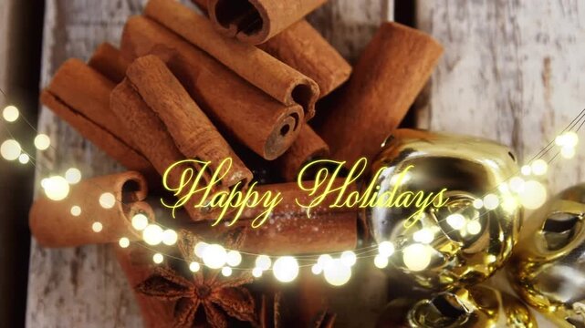 Animation of text, happy holidays, in yellow, over string lights and cinnamon sticks