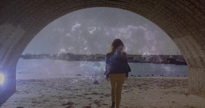 Woman stepping through brick arch onto beach sparking technology cosmic overlay swirling around her