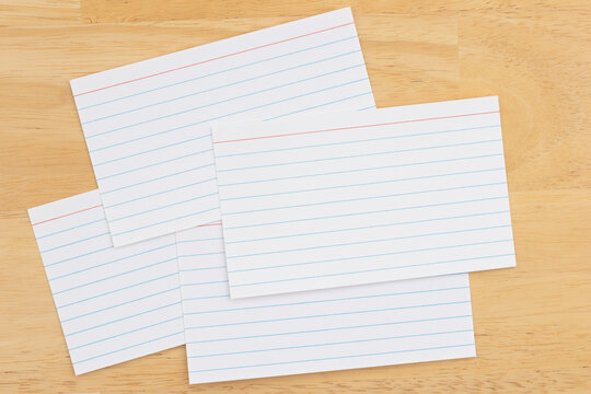 Scattered lined index cards on wooden desk