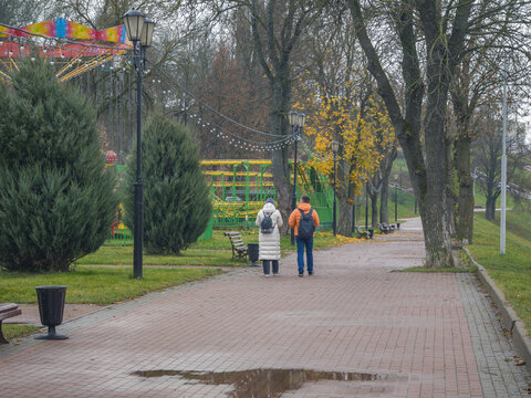 Woman and a man walk down a brick path in a park
