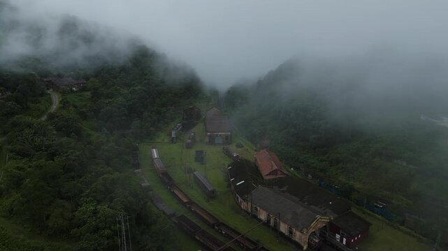 Dramatic aerial drone footage of historic Paranapiacaba village surrounded by misty Atlantic rainforest mountains with vintage funicular railway tracks, S&atilde;o Paulo, Brazil.