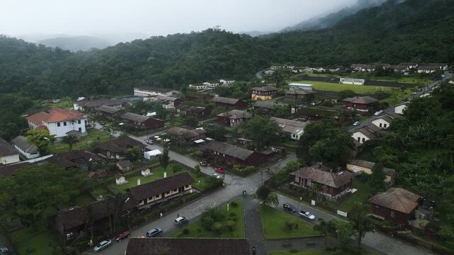 Drone footage revealing the historic railroad town of Paranapiacaba nestled in lush green mountains with fog. Traditional architecture surrounded by Atlantic rainforest in Santo Andre, Sao Paulo.
