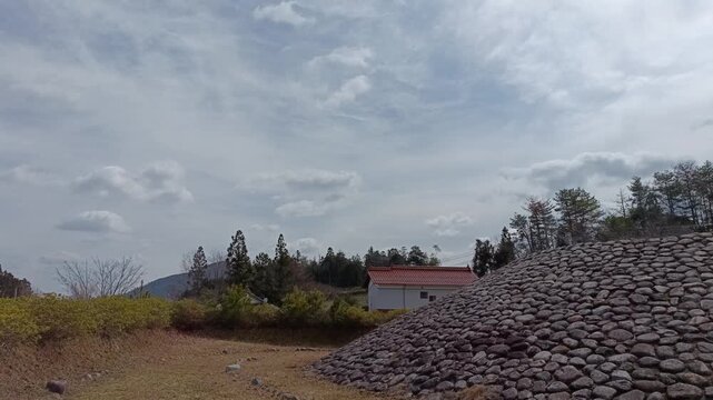 Overcast Rural Landscape with Ancient Burial Mound Stone Structure in Japanese Countryside