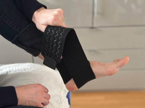 A man is applying a bandage to his joint.  How to apply a bandage to a leg for a sprained joint at home. 