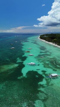 Vertical drone ascends and pulls back over boats along Bohol Beach in Panglao, Bohol