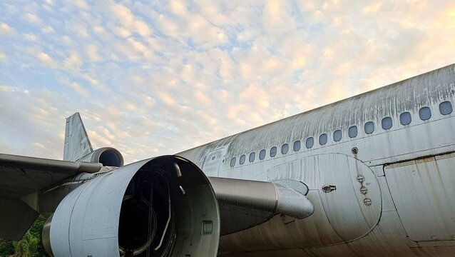 Close-up view of a weathered airplane fuselage and engine under a dramatic cloudy sky