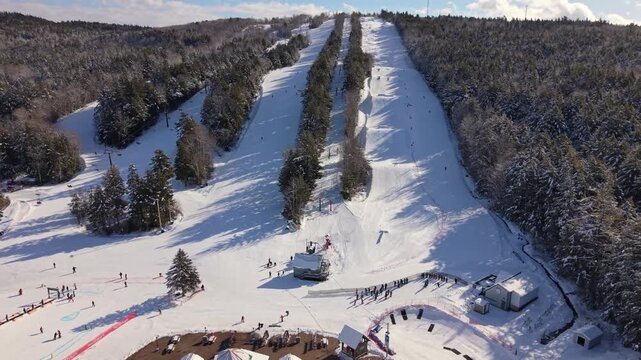 Drone high-angle view sunny winter: skiers and snowboarders enjoy Whistler Blackcomb resort. Snow-covered peaks in Nova Scotia, Canada, perfect alpine skiing conditions 4K.