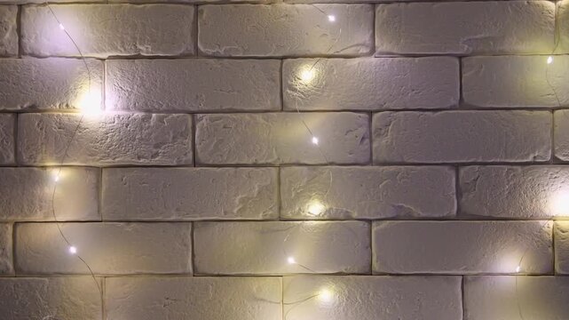 Warm white fairy lights flickering on textured beige brick wall in dark cozy setting
