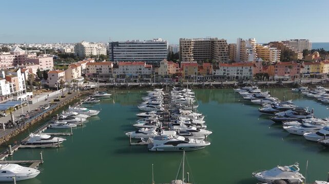 Aerial view capturing the marina&rsquo;s boats, yachts, and surrounding coastal architecture in Vilamoura, Portugal.