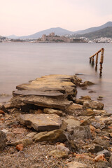 Fototapeta premium Abandoned pier and Panoramic view of Bodrum city, Turkey and Saint Peter Castle and marina. Summer landscape, popular travel destination. Selective Focus. Long Exposure shoot. tranquility scene.